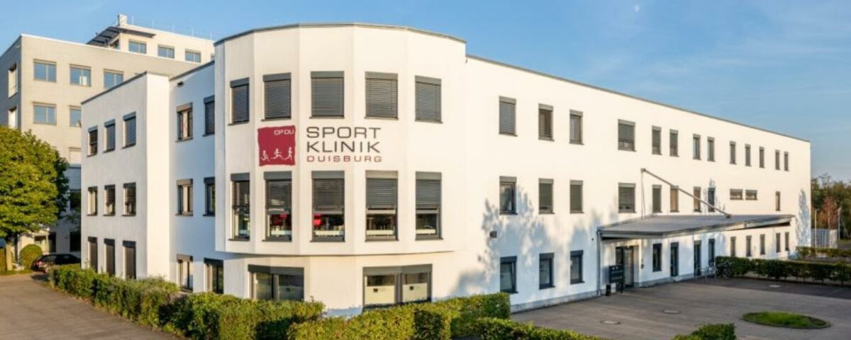 Weiße Sportklinik Duisburg in sonniger Umgebung mit grünem Eingangsbereich und moderner Architektur.
