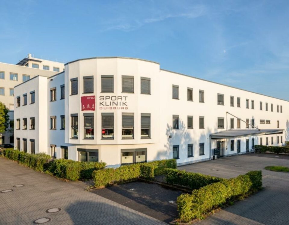 Weiße Sportklinik Duisburg in sonniger Umgebung mit grünem Eingangsbereich und moderner Architektur.