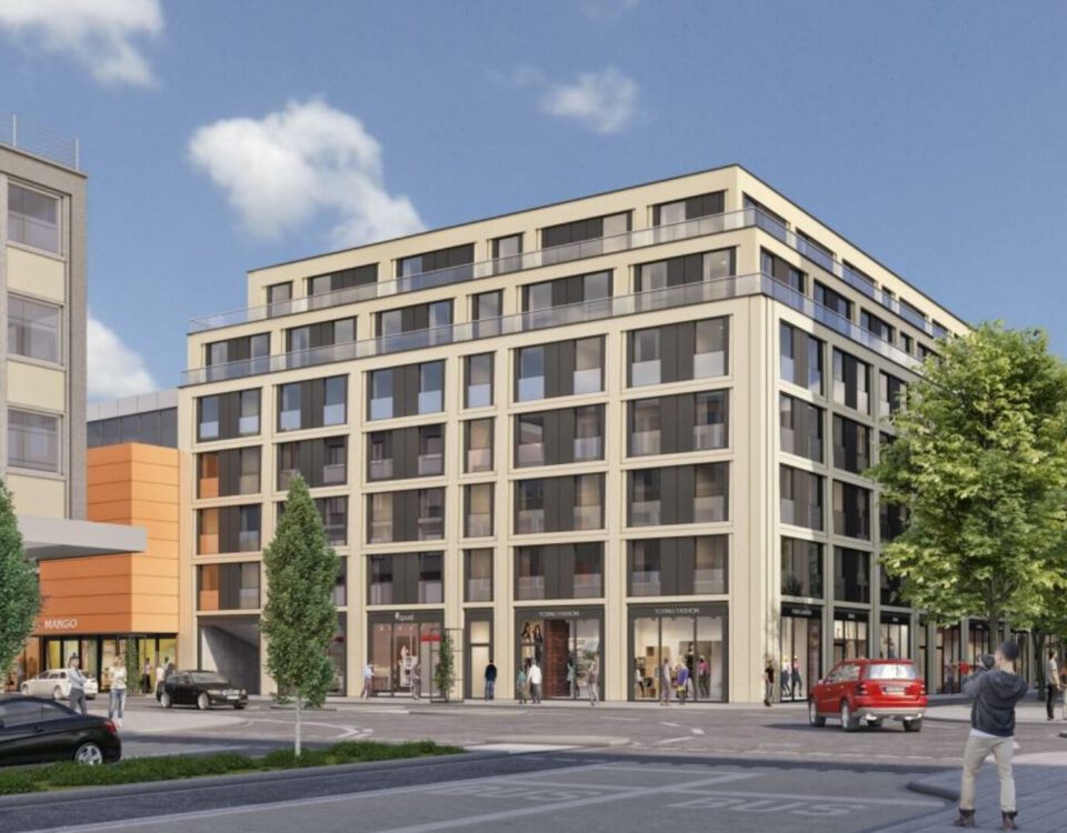 Moderne Stadtecke mit mehrstöckigem Gebäude, Geschäften und belebter Straße bei sonnigem Wetter.