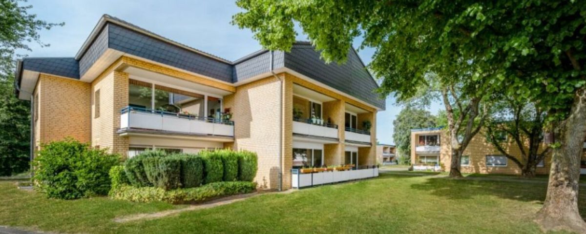 Moderner Wohnkomplex im Grünen mit Balkonen, Backstein-Fassade und gepflegter Gartenanlage, ideal für urbanes Wohnen.