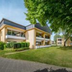 Moderner Wohnkomplex im Grünen mit Balkonen, Backstein-Fassade und gepflegter Gartenanlage, ideal für urbanes Wohnen.