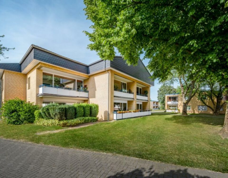 Moderner Wohnkomplex im Grünen mit Balkonen, Backstein-Fassade und gepflegter Gartenanlage, ideal für urbanes Wohnen.