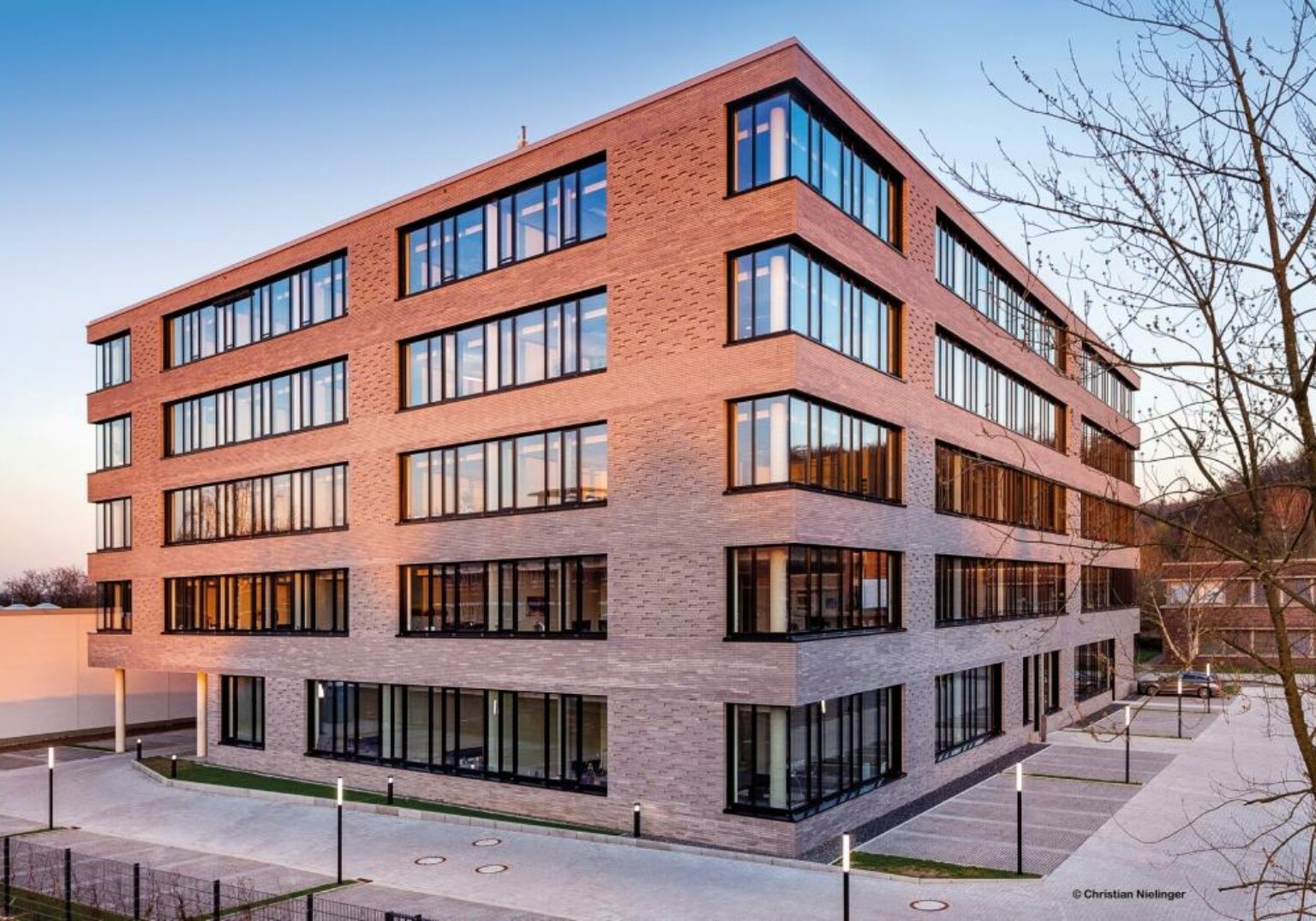 Moderne Bürogebäude-Fassade mit großen Fenstern im Sonnenuntergang, Architektur in städtischer Umgebung.