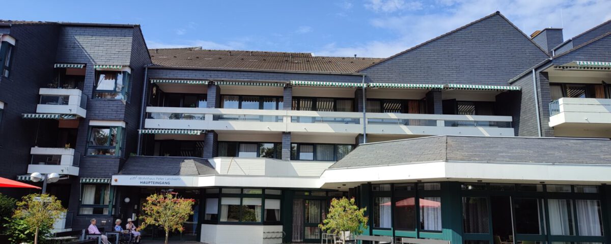Moderne Wohnanlage mit Balkonen und Sitzbereich im Außenbereich bei sonnigem Wetter.