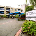 CBT Wohnhaus St. Monika mit blauen Sonnenschirmen, Hinweisschild zu Physiotherapie und Ergotherapie in Köln.