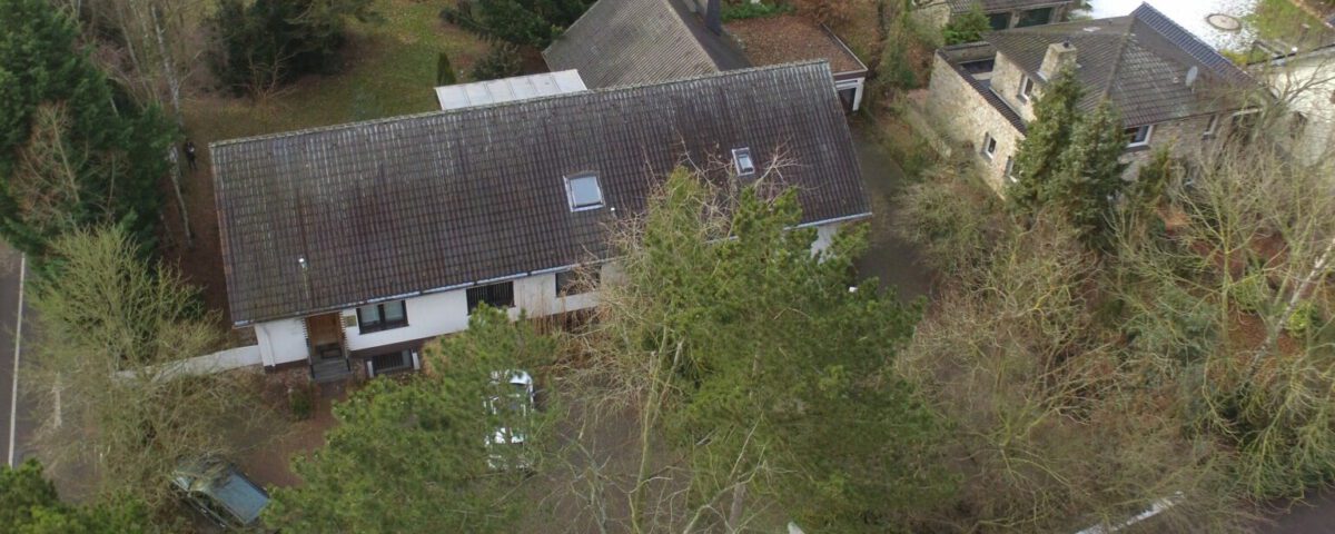 Luftaufnahme eines Einfamilienhauses mit einem großen Garten, umgeben von Bäumen, in einer ruhigen Nachbarschaft.