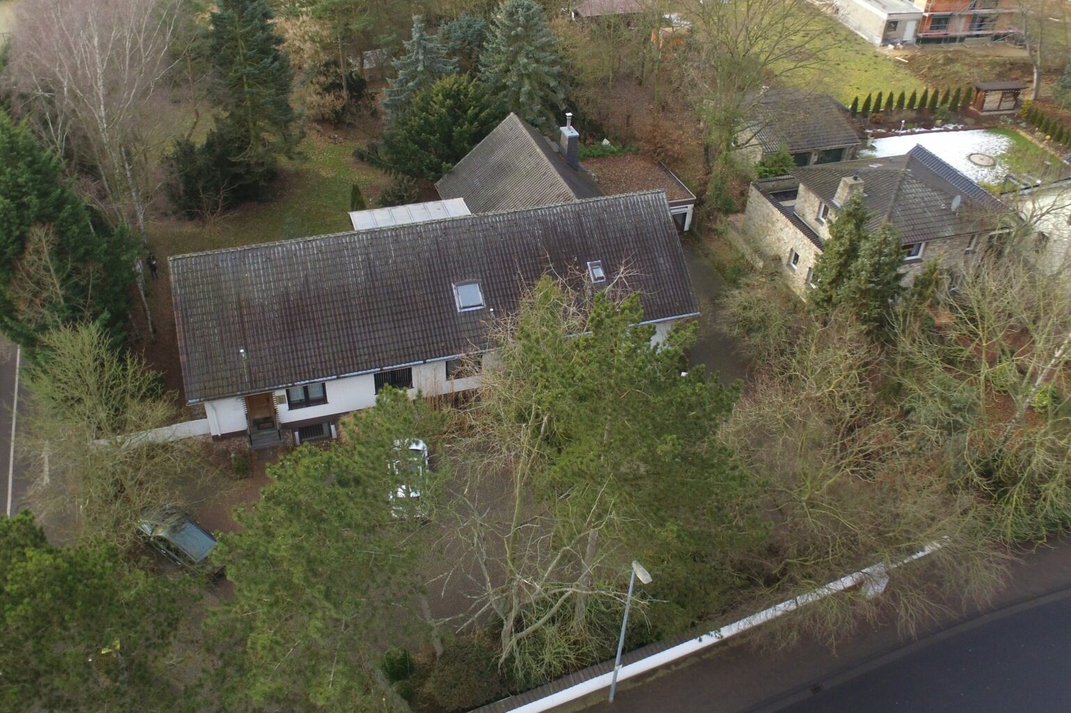 Luftaufnahme eines Einfamilienhauses mit einem großen Garten, umgeben von Bäumen, in einer ruhigen Nachbarschaft.