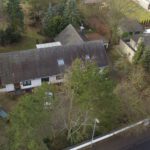 Luftaufnahme eines Hauses mit Garten, umgeben von Bäumen, in einem Wohngebiet.