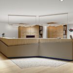Moderne Empfangstheke mit TFP-Branding in hellem Bürogebäude, mit minimalistischer Holzoptik und einladender Atmosphäre.