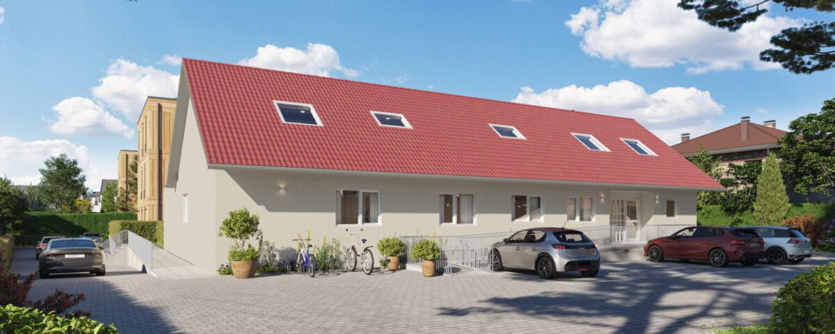Moderner Neubau mit rotem Dach, umgeben von Autos, Fahrrädern und Grünflächen in einem sonnigen Wohngebiet.
