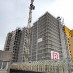 Hochhaus mit Baugerüst und Kran im Umbau, moderne Architektur, bewölkter Himmel im Hintergrund.