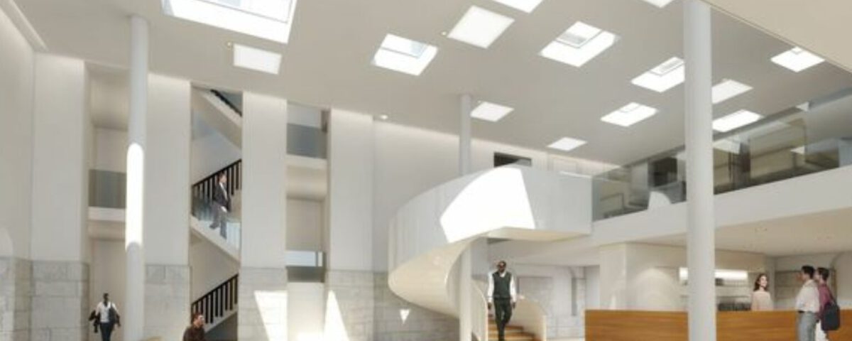 Modernes, lichtdurchflutetes Atrium mit Wendeltreppe, minimalistischen Sitzgelegenheiten und Personen im Gespräch.
