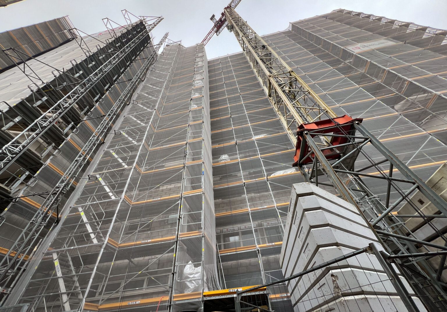Baustelle mit eingerüstetem Hochhaus und Kran, im Bauprozess für modernes Stadtentwicklungsprojekt.