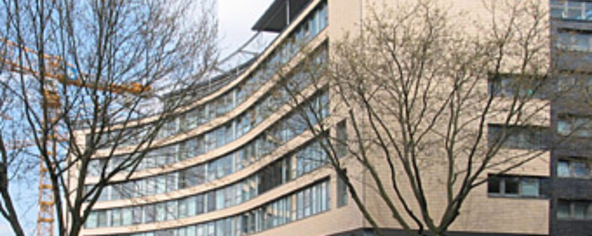 Moderne Architektur eines geschwungenen Bürogebäudes mit Glasfassade an einem sonnigen Tag.