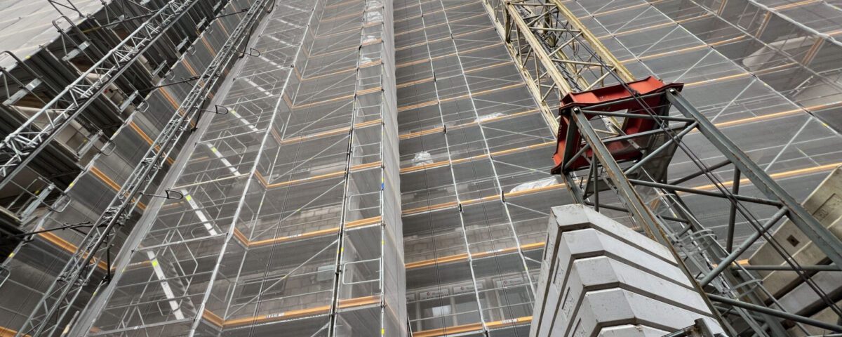 Baustelle mit Gerüst und Kran, Fortschritt Hochhausbau, moderner städtischer Wohnraum im Bau.