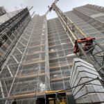 Baustelle mit Gerüst und Kran, Fortschritt Hochhausbau, moderner städtischer Wohnraum im Bau.