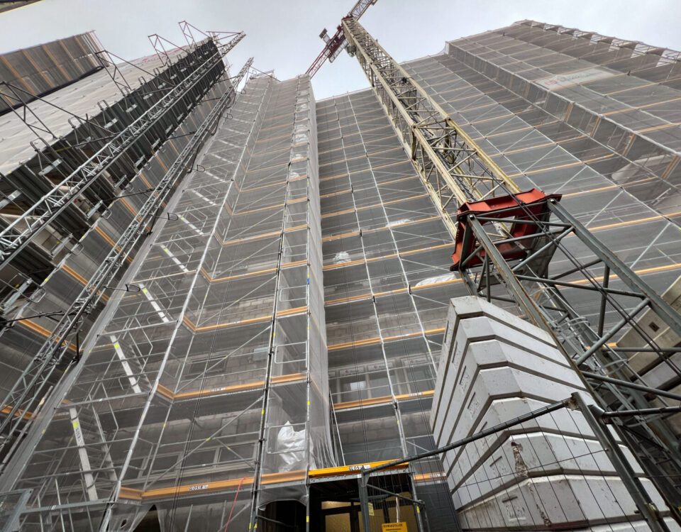 Baustelle mit Gerüst und Kran, Fortschritt Hochhausbau, moderner städtischer Wohnraum im Bau.