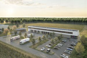 Moderne Logistikzentrale mit Lkw, Solarzellen und Parkplätzen, umgeben von Wald und Feldern unter bewölktem Himmel.
